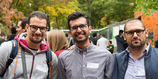 three men standing next to each other and smiling into the camera