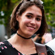 Skorokhod Testimonial Ein Porträt einer jungen Frau. Sie hat eine Sonnenbrille in die Haare geschoben. Im Hintergund ist ein Baum zu sehen.