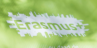 Erasmus Plus Flagge Schriftzug "Erasmus+" auf einem grünen Stoff