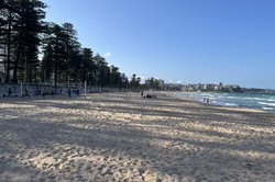 Strand mit vielen Beach Volleyball Plätzen links und Wasser rechts. Die Stadt sieht man im Hintergrund.